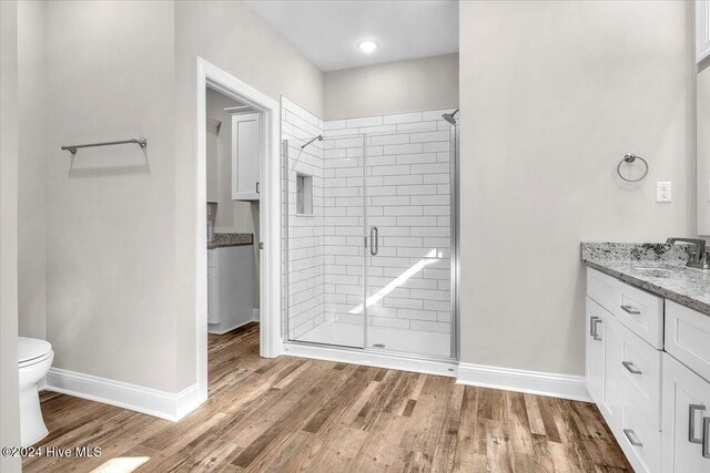 bathroom featuring hardwood / wood-style floors, vanity, toilet, and a shower with door