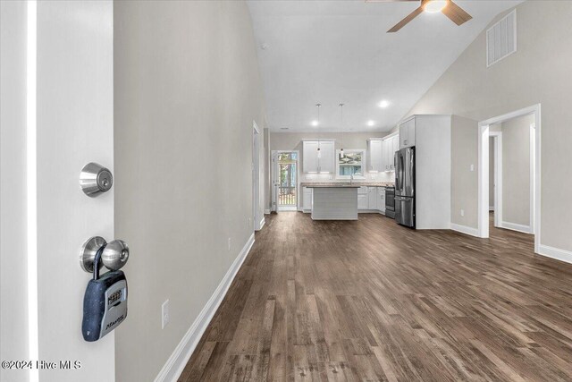 unfurnished living room featuring dark hardwood / wood-style flooring, high vaulted ceiling, ceiling fan, and sink