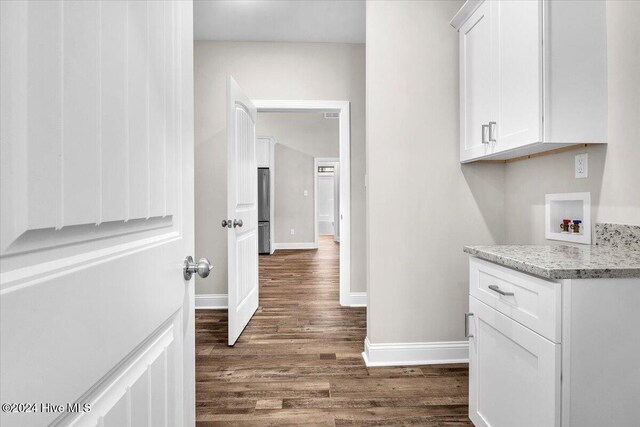 interior space with cabinets, hookup for a washing machine, and dark hardwood / wood-style floors