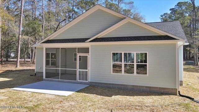 rear view of house featuring a sunroom and a patio