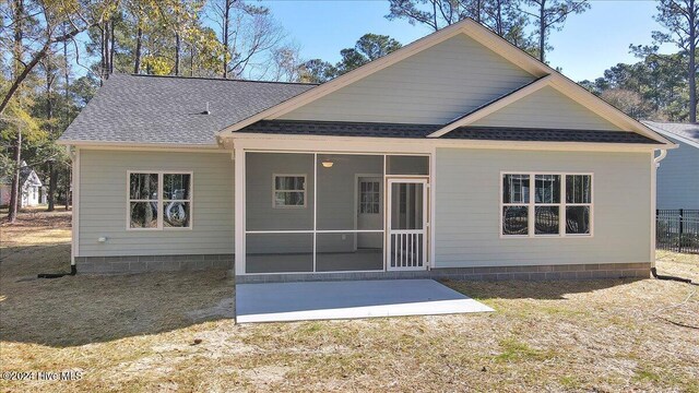 back of house featuring a lawn, a patio area, and a sunroom