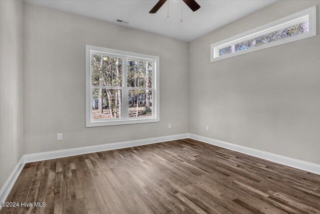 unfurnished room with dark wood-type flooring, ceiling fan, and a healthy amount of sunlight