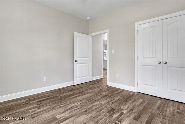 unfurnished bedroom with dark hardwood / wood-style flooring and a closet