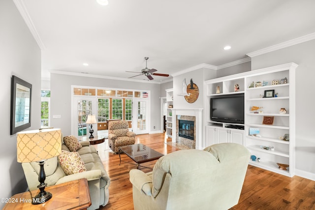 living room with ceiling fan, light wood-type flooring, and crown molding