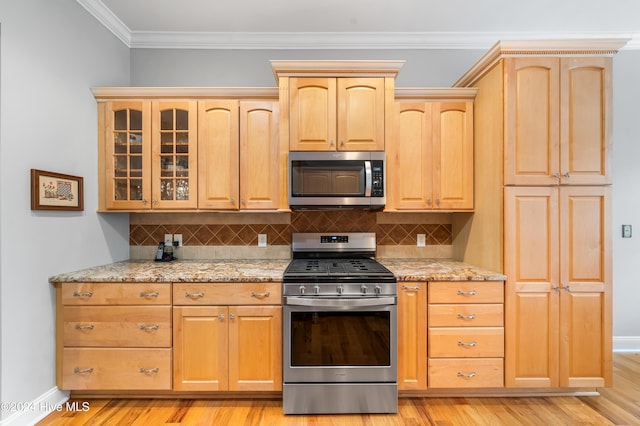 kitchen with light hardwood / wood-style floors, light stone countertops, stainless steel appliances, and tasteful backsplash