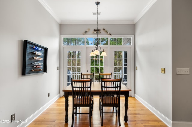 dining room with light hardwood / wood-style floors, an inviting chandelier, and crown molding