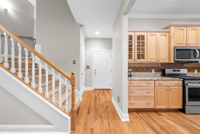 kitchen featuring tasteful backsplash, stainless steel appliances, crown molding, light brown cabinets, and light hardwood / wood-style floors