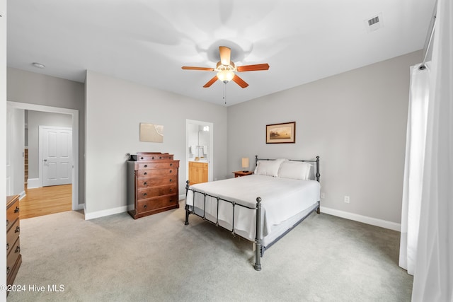 bedroom with ensuite bath, ceiling fan, and light colored carpet