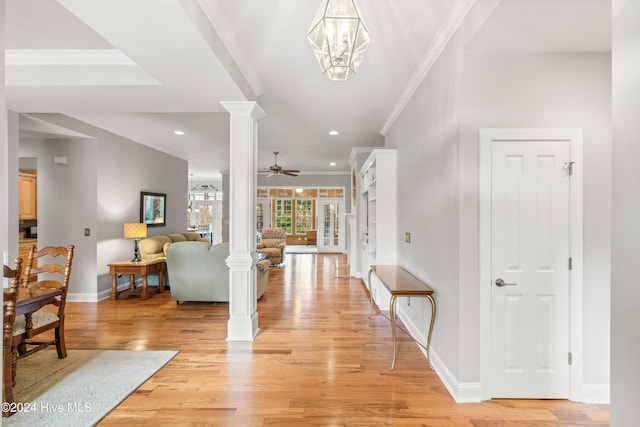 foyer featuring ceiling fan with notable chandelier, light hardwood / wood-style floors, ornate columns, and crown molding