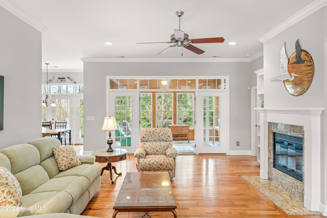 living room with a high end fireplace, light hardwood / wood-style floors, plenty of natural light, and ornamental molding