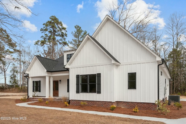 modern inspired farmhouse featuring covered porch, roof with shingles, cooling unit, and board and batten siding