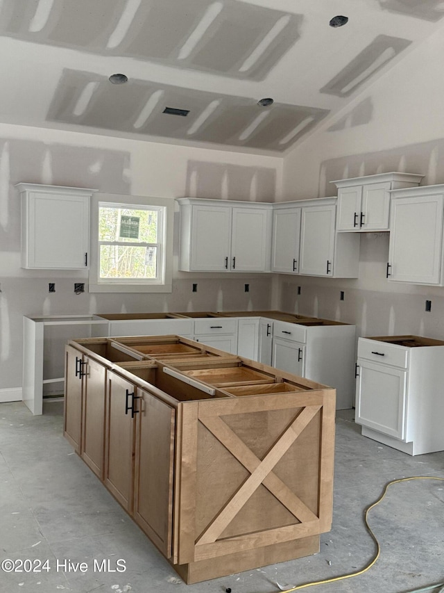 kitchen featuring white cabinetry, a kitchen island, and vaulted ceiling