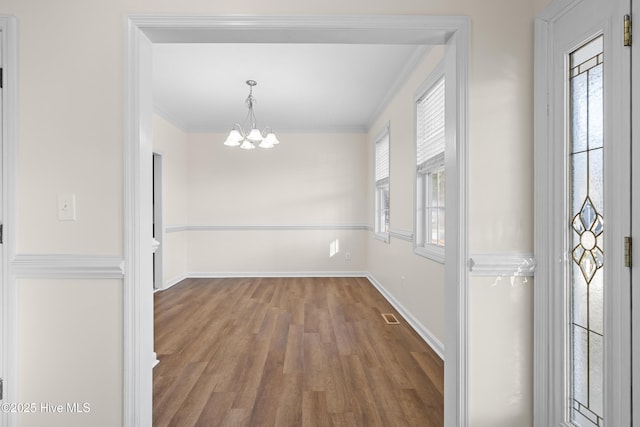 unfurnished dining area featuring crown molding, plenty of natural light, and an inviting chandelier