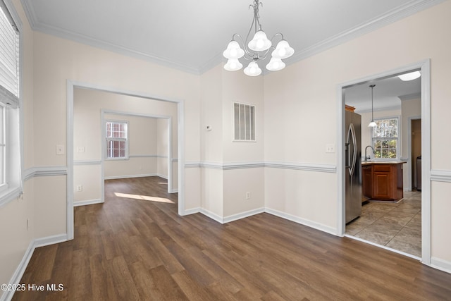 unfurnished dining area featuring dark hardwood / wood-style flooring, ornamental molding, sink, and a chandelier