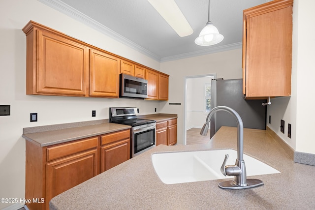 kitchen with sink, pendant lighting, crown molding, and stainless steel appliances