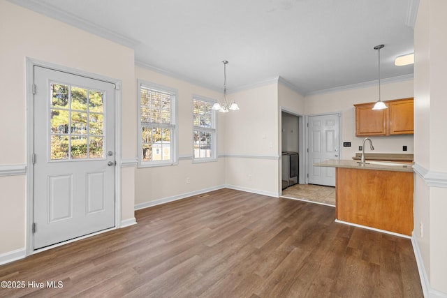 kitchen featuring a notable chandelier, ornamental molding, decorative light fixtures, and washer / dryer