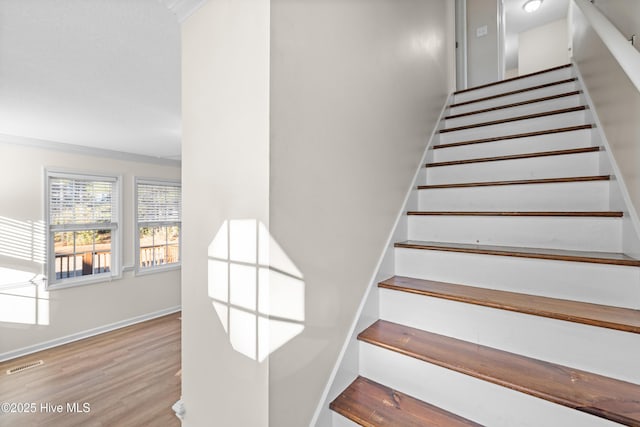 stairs featuring wood-type flooring and ornamental molding