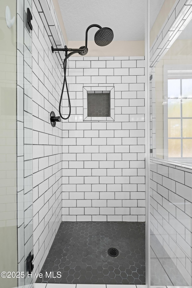 bathroom featuring a textured ceiling and a shower with shower door