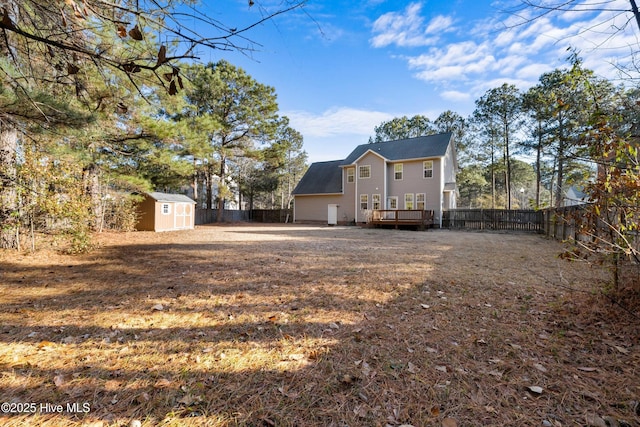 rear view of property with a storage unit and a wooden deck