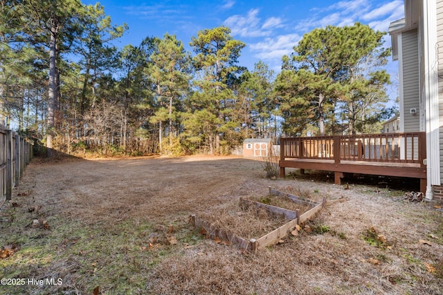 view of yard featuring a wooden deck and a storage unit