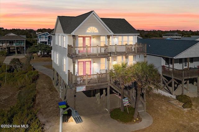 back house at dusk featuring a balcony and french doors