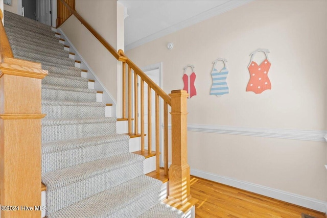 stairway with hardwood / wood-style floors and crown molding