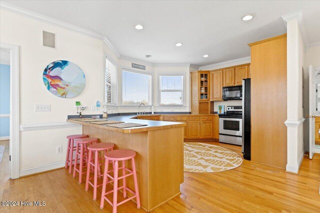 kitchen with a breakfast bar, electric range, light hardwood / wood-style flooring, and crown molding