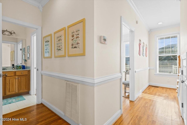 hall with light hardwood / wood-style floors and crown molding