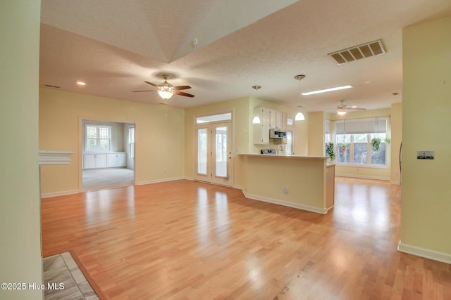 unfurnished living room featuring ceiling fan, a textured ceiling, and light hardwood / wood-style flooring