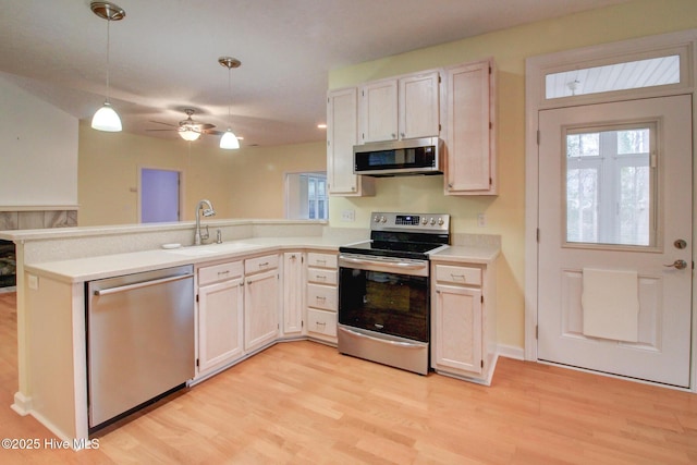 kitchen with sink, ceiling fan, decorative light fixtures, kitchen peninsula, and stainless steel appliances