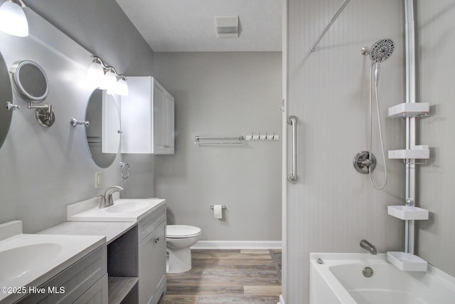 full bathroom featuring wood-type flooring, a textured ceiling, toilet, vanity, and bathtub / shower combination