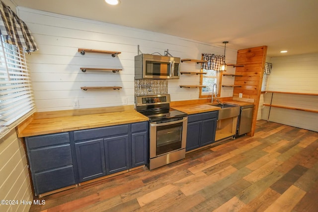 kitchen with wood counters, decorative light fixtures, stainless steel appliances, and a healthy amount of sunlight