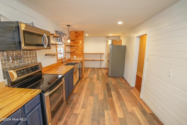 kitchen with hardwood / wood-style floors, wooden counters, and stainless steel appliances