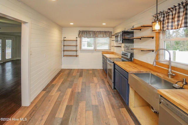 kitchen with pendant lighting, butcher block countertops, stainless steel appliances, and dark wood-type flooring