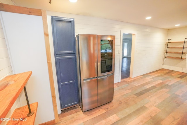 kitchen featuring stainless steel refrigerator, light hardwood / wood-style floors, and blue cabinets