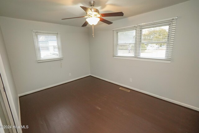 unfurnished bedroom featuring ceiling fan, dark hardwood / wood-style floors, a closet, and multiple windows