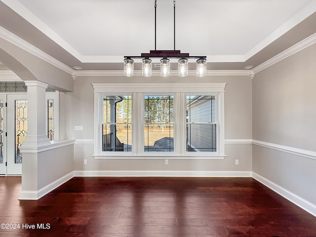 unfurnished dining area featuring a tray ceiling, ornate columns, dark hardwood / wood-style flooring, and ornamental molding