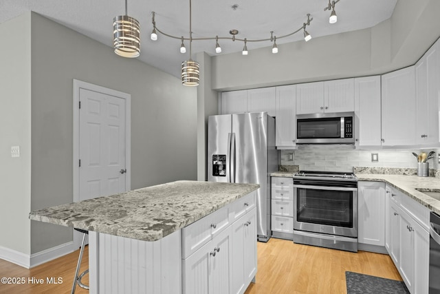 kitchen with stainless steel appliances, decorative light fixtures, and white cabinetry