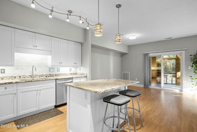 kitchen featuring stainless steel dishwasher, pendant lighting, a center island, white cabinetry, and sink