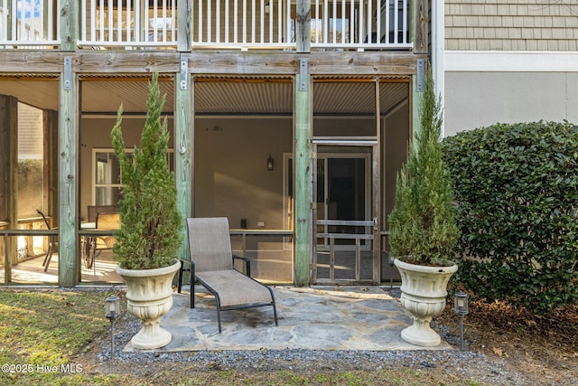 view of exterior entry with a balcony and a patio