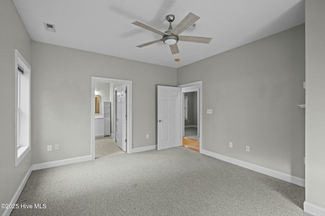 unfurnished bedroom featuring multiple windows, ceiling fan, light carpet, and connected bathroom