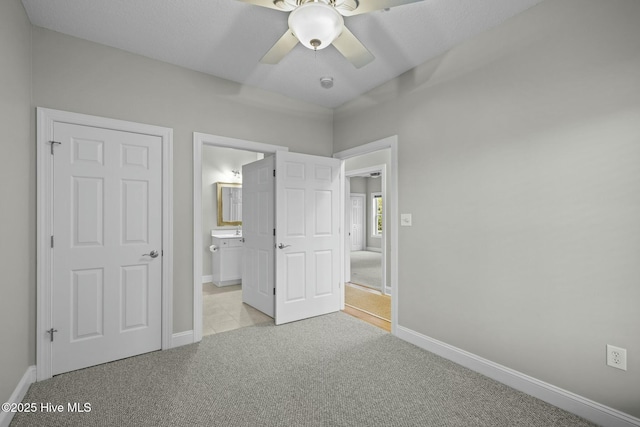 unfurnished bedroom featuring ceiling fan, connected bathroom, and light carpet