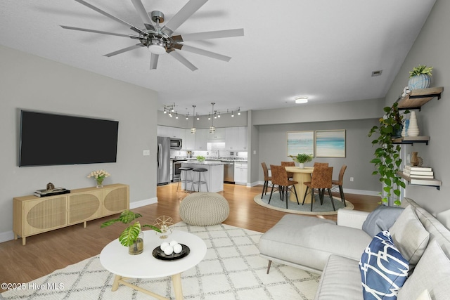 living room with sink, ceiling fan, and light hardwood / wood-style flooring