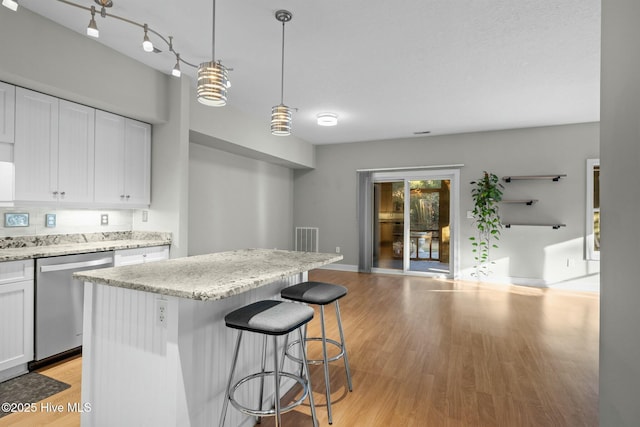 kitchen with a kitchen island, stainless steel dishwasher, hanging light fixtures, and white cabinetry