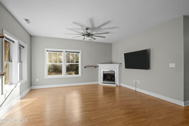 unfurnished living room with a textured ceiling, ceiling fan, and light hardwood / wood-style flooring