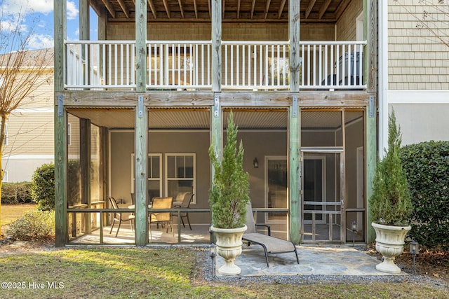 back of property with a balcony, a sunroom, and a patio area