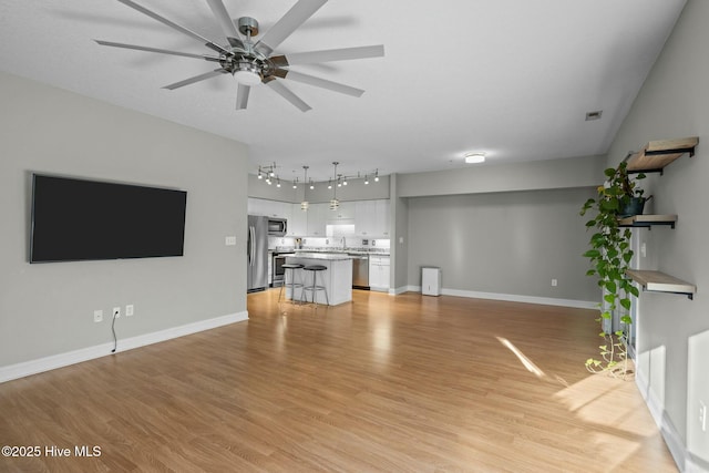 unfurnished living room featuring ceiling fan, light hardwood / wood-style floors, and sink