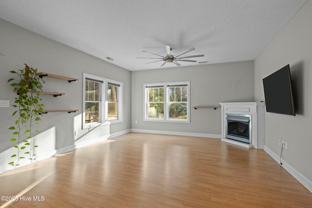 unfurnished living room with a textured ceiling, ceiling fan, and light hardwood / wood-style floors