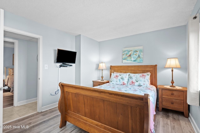 bedroom with light hardwood / wood-style floors and a textured ceiling