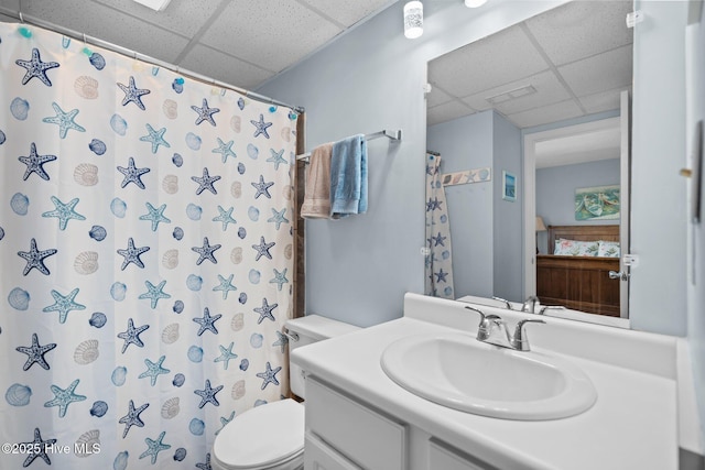 bathroom with a paneled ceiling, vanity, a shower with shower curtain, and toilet